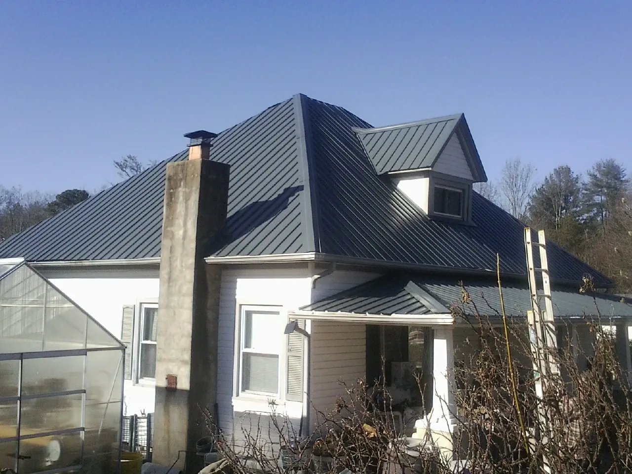 Dark blue standing seam metal roof on a white farmhouse with dormer — Slate & Tile Roof Repair by Roofing Brothers in Holt