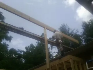 Carpenter setting a ridge beam over a new addition frame — Ice Dam Removal by Roofing Brothers in Holt
