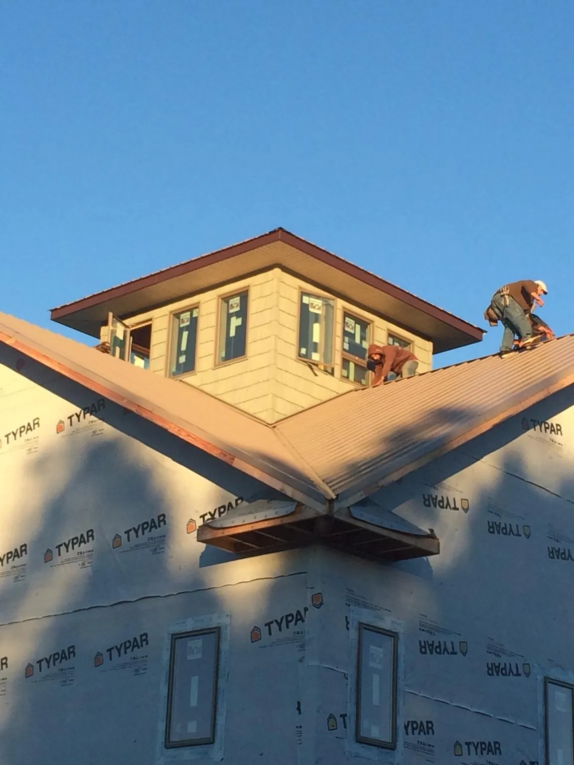Roofers working around a rooftop cupola on a new metal roof at sunset — Roof Waterproofing in Holt by Roofing Brothers
